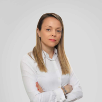 Mirjana-Lalosevic-square-portrait-EIT-food-webpage Portrait of a woman in a white shirt with long straight blonde hair, standing with folded arms against a light grey background.
