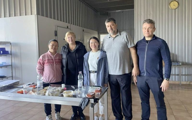 NewsletterDec25-experts-Angromix-77 A group of people standing together in a tofu production facility beside a table with soya product samples.