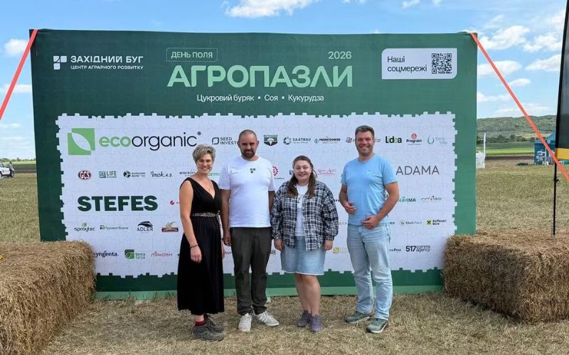 Four people stand in front of a Zakhidnyi Buh 2026 field-day banner showing soya, sugar beet and maize.